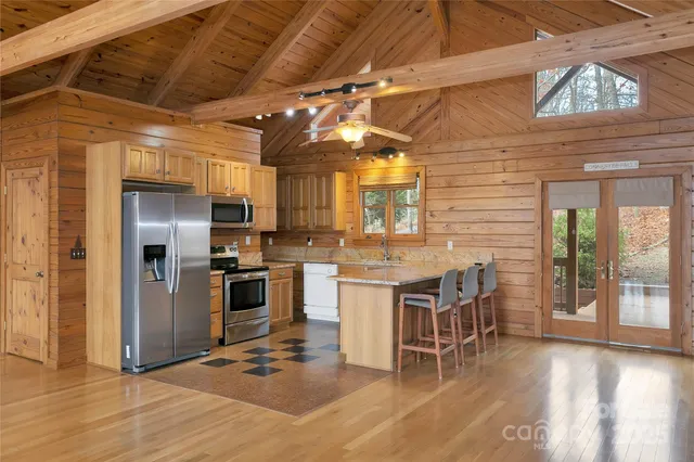 a kitchen with stainless steel appliances granite countertop a stove a refrigerator a sink a dining table and chairs with wooden floor