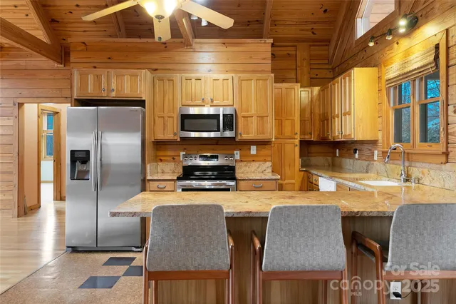 a kitchen with stainless steel appliances granite countertop a refrigerator a stove a sink a dining table and chairs with wooden floor