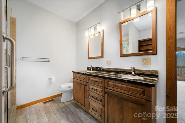 a bathroom with a granite countertop sink toilet and mirror