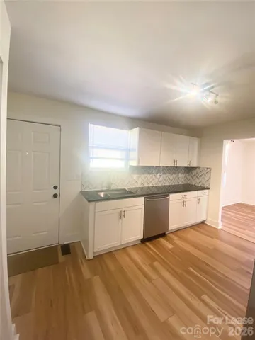 a kitchen with granite countertop a sink cabinets and wooden floor