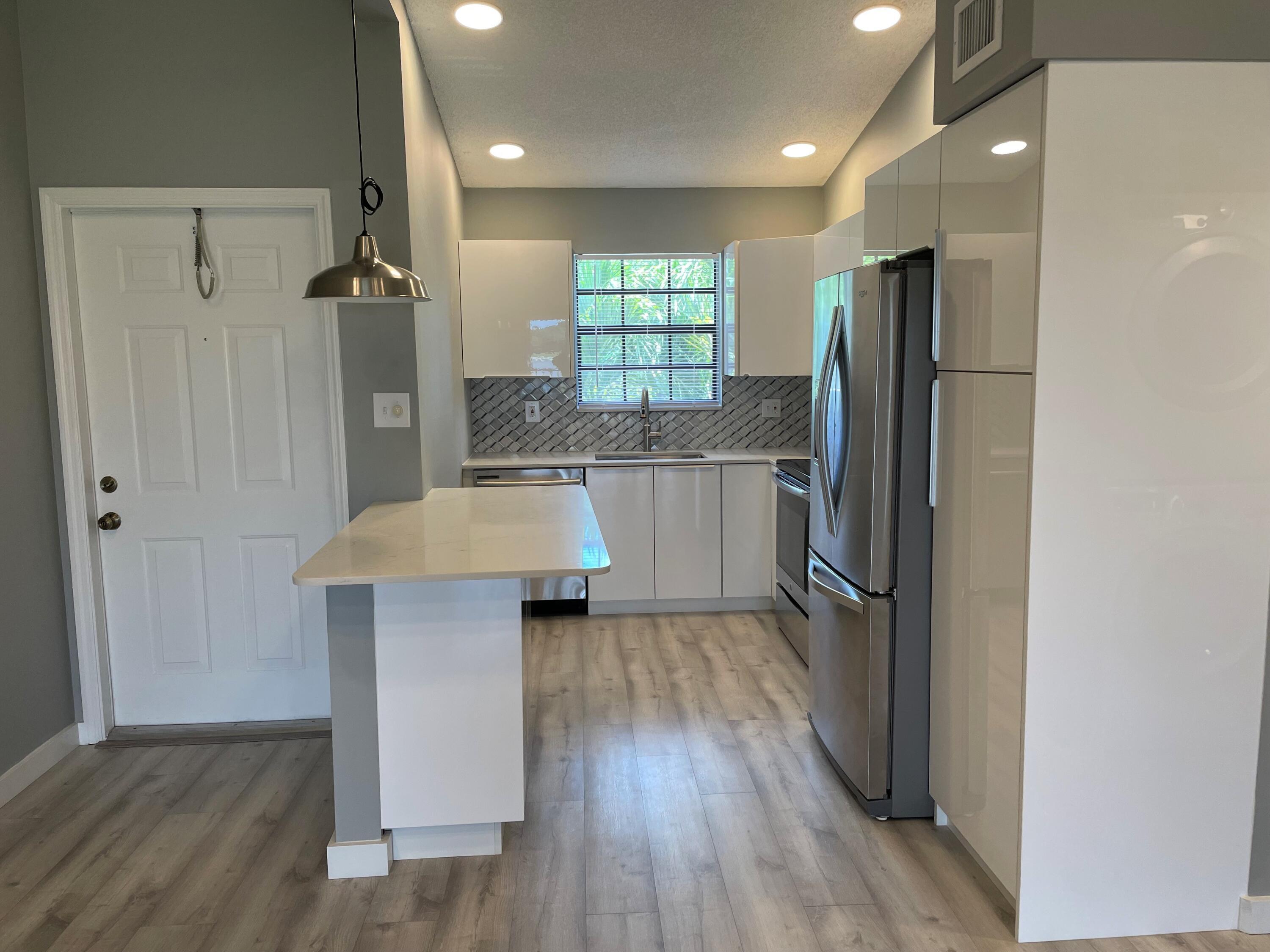2800 Palmwood Terrace, Unit P221 Boca Raton, FL 33431 - Photo 3 of 16 a kitchen with kitchen island a counter top space a refrigerator and a sink