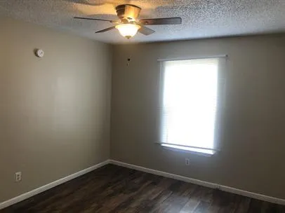 an empty room with a window and a fan