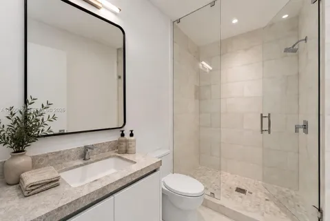 a bathroom with a granite countertop sink a toilet and a mirror