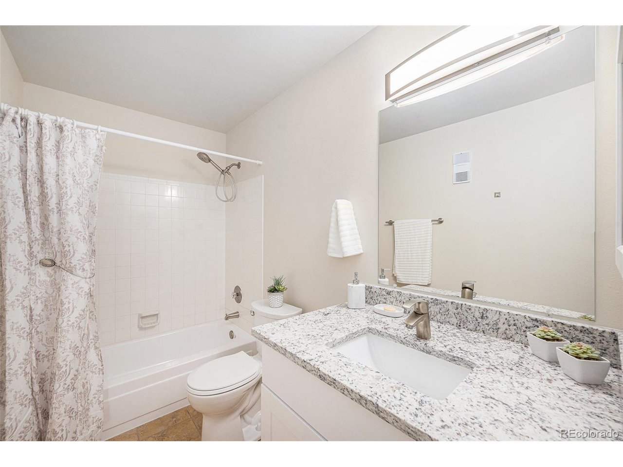 10251 West 44th Avenue, Unit 204 Wheat Ridge, CO 80033 - Photo 5 of 13 a bathroom with a granite countertop sink toilet a large mirror a bathtub and shower