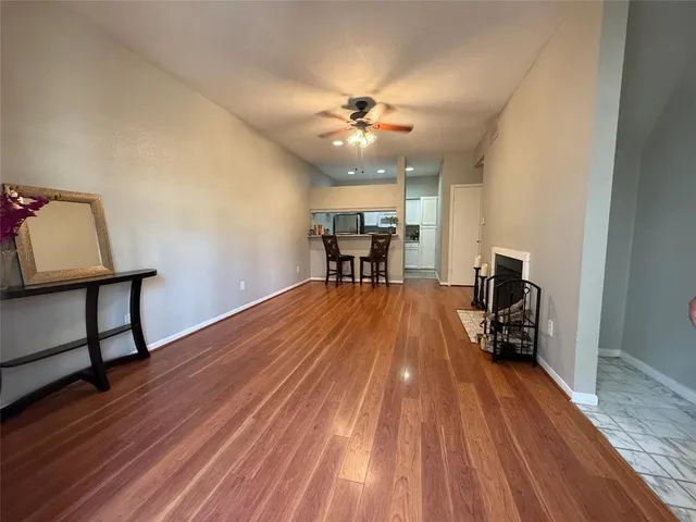 a dining room with wooden floor a chandelier fan and a window