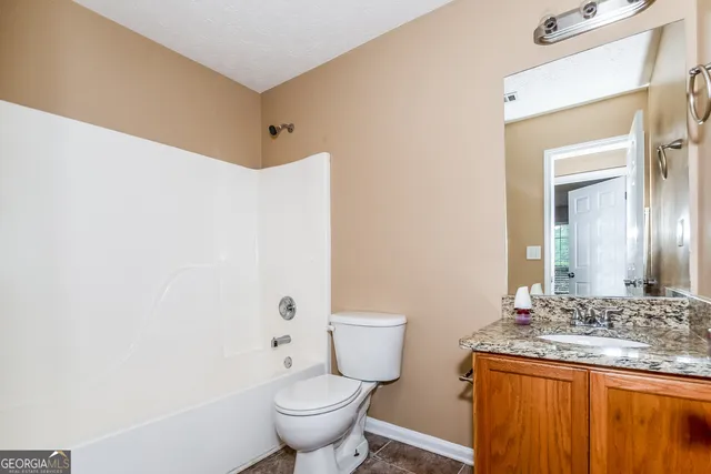 a bathroom with a granite countertop sink toilet and mirror