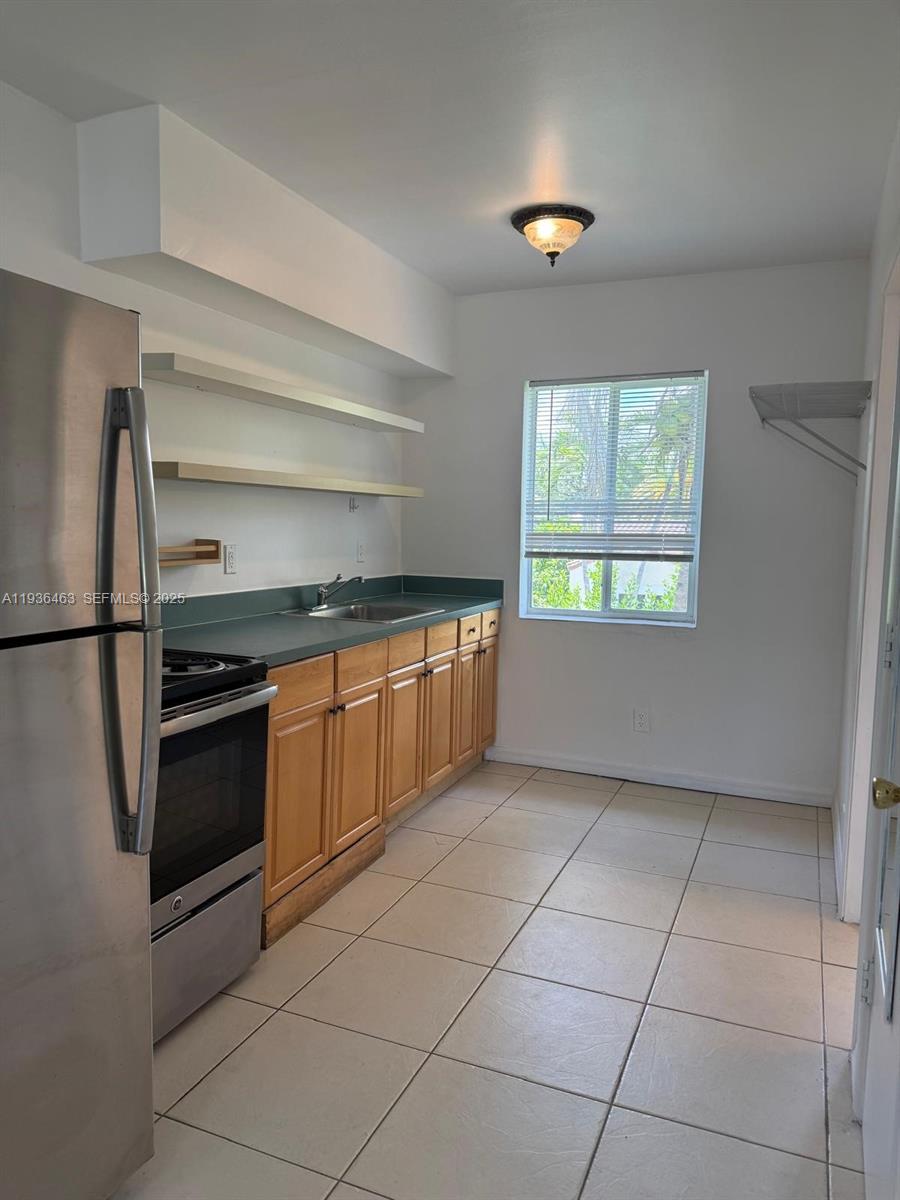 680 Northeast 88th Terrace, Unit 11 Miami, FL 33138 - Photo 3 of 8 a kitchen with a stove a microwave and a refrigerator