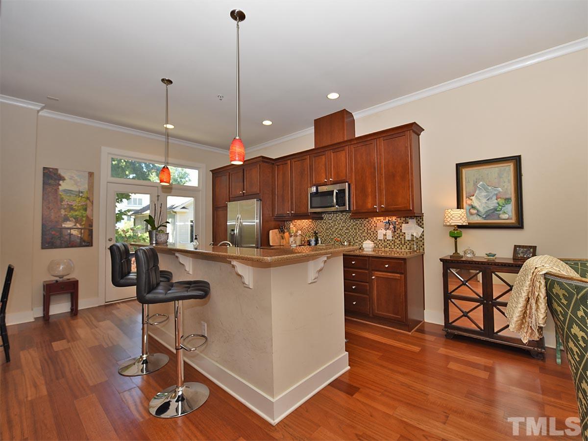520 John Haywood Way, Unit 102 Raleigh, NC 27604 - Photo 6 of 18 a kitchen with stainless steel appliances granite countertop a refrigerator a stove top oven a sink dishwasher a dining table and chairs with wooden floor