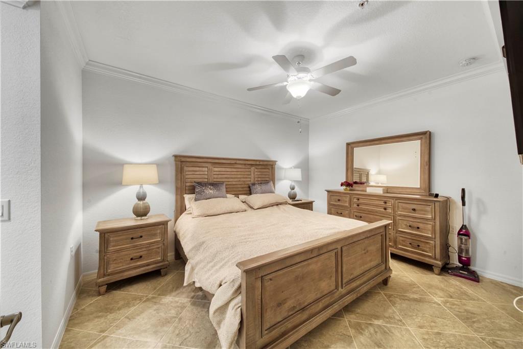 9572 Trevi Court, Unit 5017 Naples, FL 34113 - Photo 11 of 25 a bedroom with a bed and a tv on the dresser