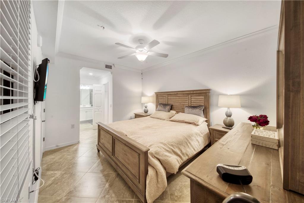 9572 Trevi Court, Unit 5017 Naples, FL 34113 - Photo 13 of 25 a bedroom with a bed and a flat tv screen on wall