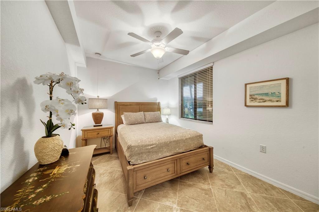 9572 Trevi Court, Unit 5017 Naples, FL 34113 - Photo 15 of 25 a bedroom with a bed and a chandelier