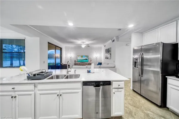 a kitchen with stainless steel appliances kitchen island granite countertop a sink a refrigerator and cabinets