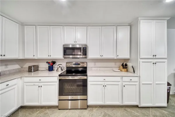 a kitchen with white cabinets and white appliances