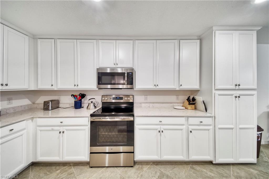 9572 Trevi Court, Unit 5017 Naples, FL 34113 - Photo 5 of 25 a kitchen with white cabinets and white appliances