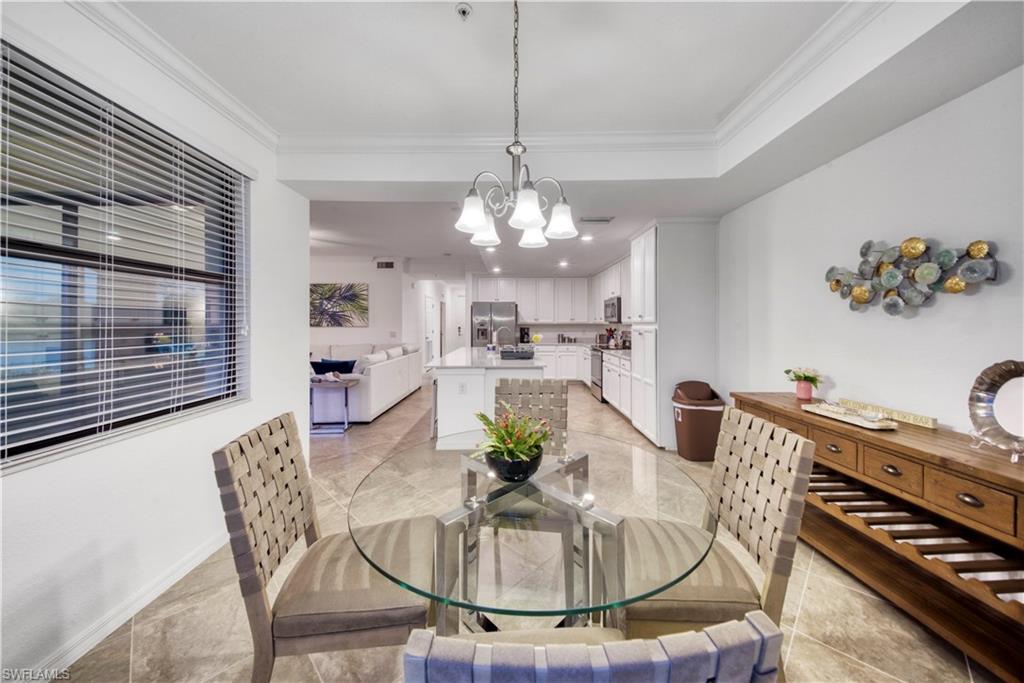 9572 Trevi Court, Unit 5017 Naples, FL 34113 - Photo 7 of 25 a dining room with furniture a rug and a chandelier