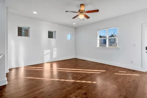 a view of an empty room with window and wooden floor