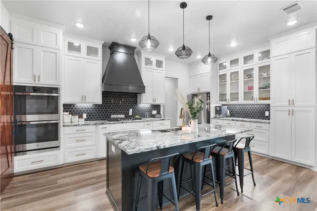 a kitchen with stainless steel appliances granite countertop a stove and a wooden floor