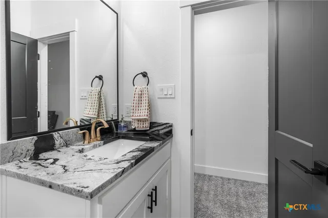 a bathroom with a granite countertop sink and a mirror