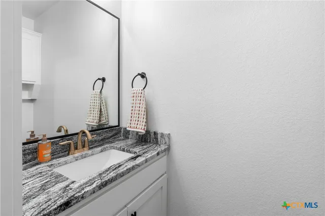 a bathroom with a granite countertop sink and a mirror