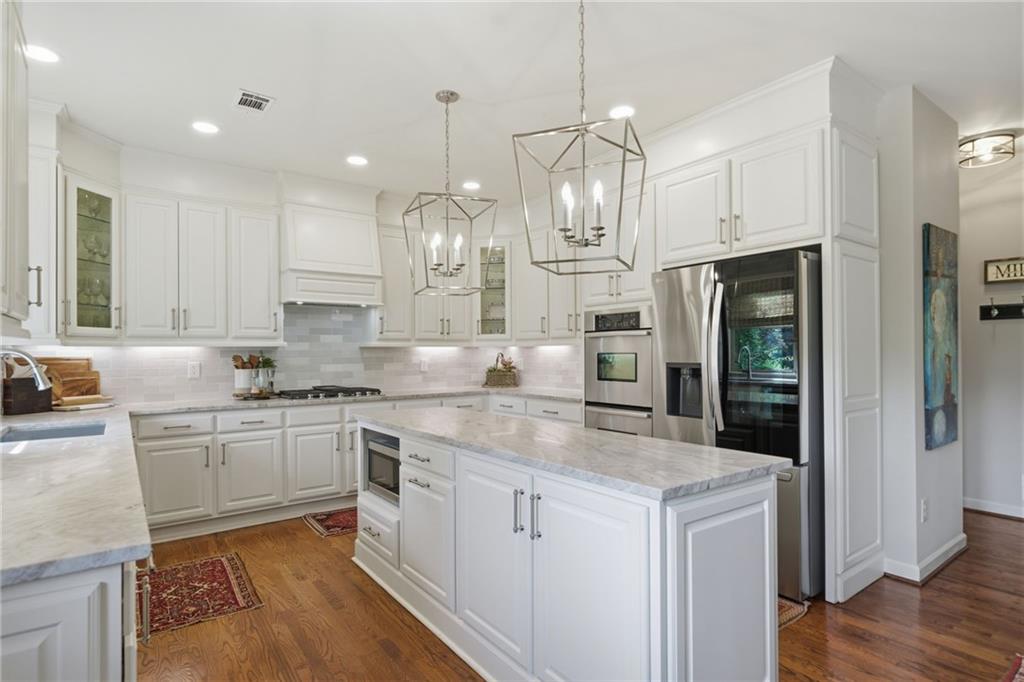 535 Brayford Way Suwanee, GA 30024 - Photo 16 of 55 a kitchen with stainless steel appliances granite countertop a sink a stove a refrigerator and white cabinets with wooden floor