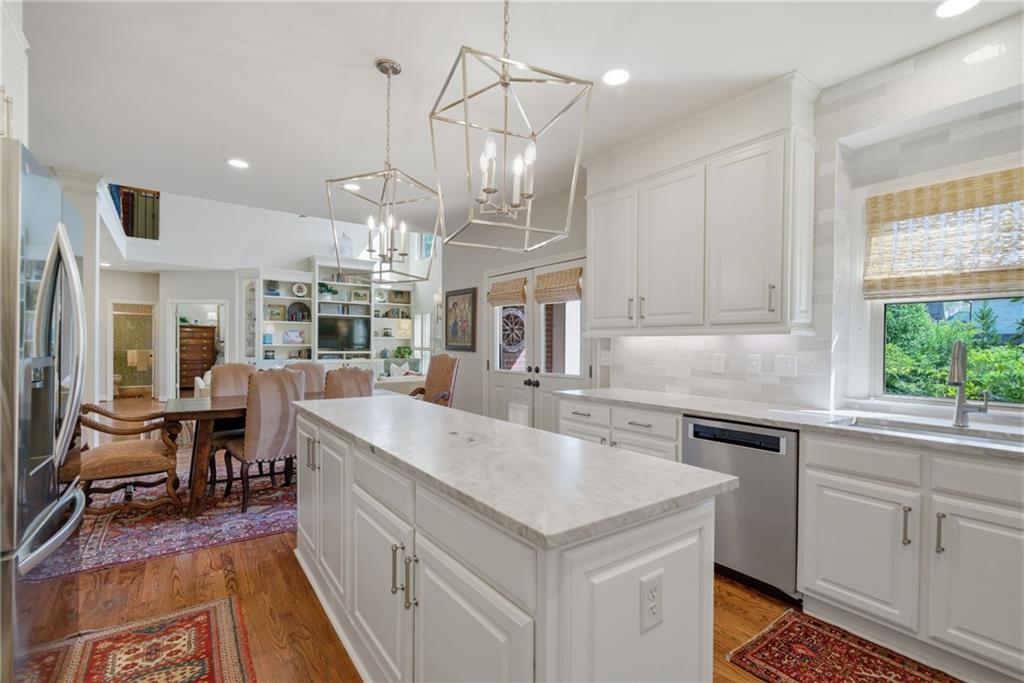 535 Brayford Way Suwanee, GA 30024 - Photo 18 of 55 a open kitchen with stainless steel appliances granite countertop a sink dishwasher a stove a dining table and chairs with wooden floor