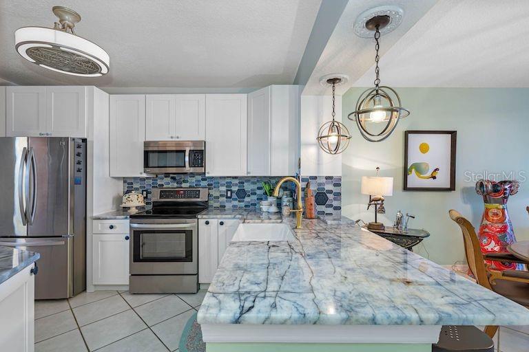 16550 Gulf Boulevard, Unit 545 North Redington Beach, FL 33708 - Photo 10 of 64 a kitchen with stainless steel appliances granite countertop a sink a stove microwave and cabinets