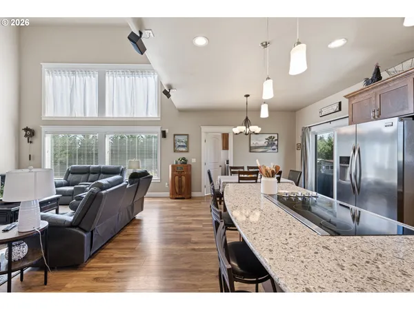 a large living room with stainless steel appliances granite countertop a couch a rug kitchen view and large windows