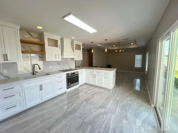 a large kitchen with stainless steel appliances kitchen island granite countertop a stove a sink and white cabinets