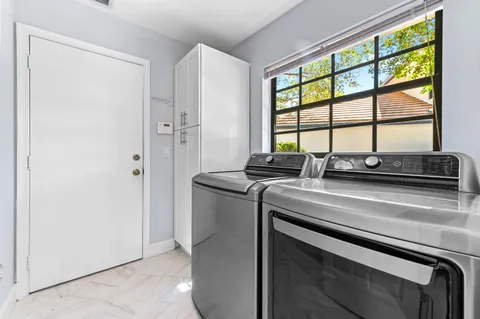 a utility room with stainless steel appliances a sink and a window