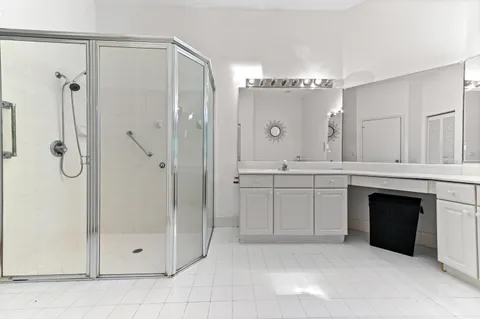 a spacious bathroom with a shower a sink and a mirror