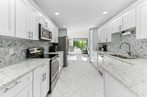 a large kitchen with stainless steel appliances granite countertop a sink a stove and cabinets