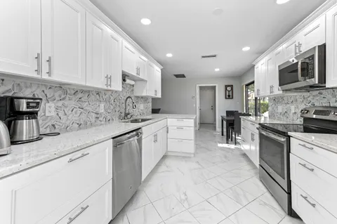 a large white kitchen with stainless steel appliances granite countertop lots of counter top space