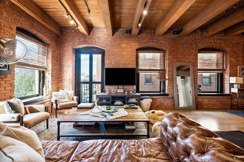 a living room with a couch wooden floor and a large window