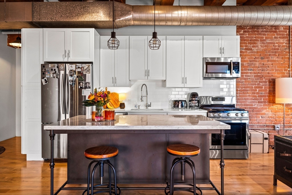 21 Wormwood Street, Unit 412 Boston, MA 02210 - Photo 5 of 11 a kitchen with stainless steel appliances granite countertop a stove refrigerator sink and cabinets