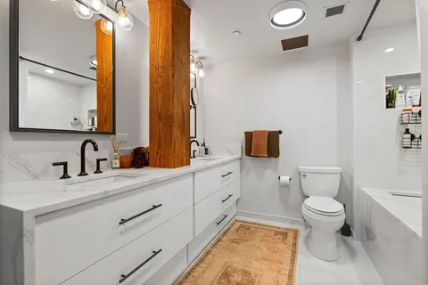 a bathroom with a granite countertop toilet sink and mirror