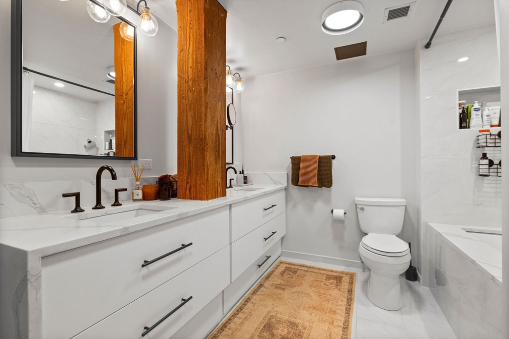 21 Wormwood Street, Unit 412 Boston, MA 02210 - Photo 10 of 11 a bathroom with a granite countertop toilet sink and mirror