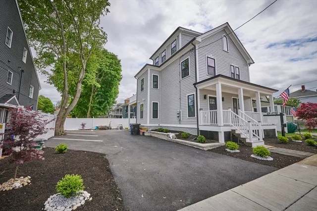 a view of a white house with a yard and a street