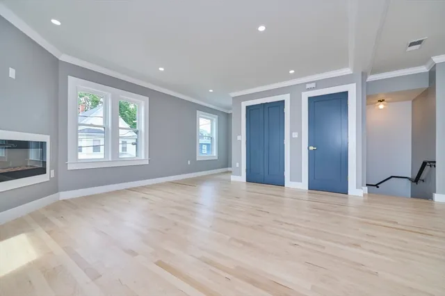 a view of an empty room with window and wooden floor