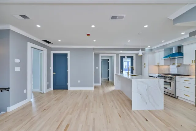 a large kitchen with stainless steel appliances granite countertop a large counter top and wooden floors