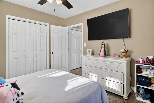 a bedroom with a bed and a flat tv screen on dresser