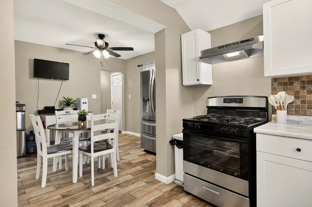 a kitchen with stainless steel appliances a stove a microwave and white cabinets