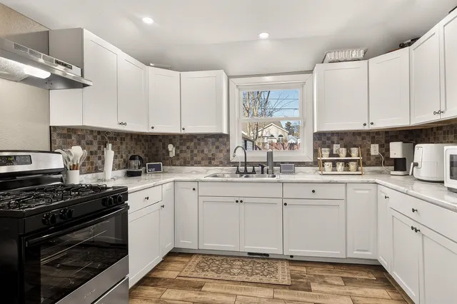a kitchen with granite countertop a sink stove and cabinets