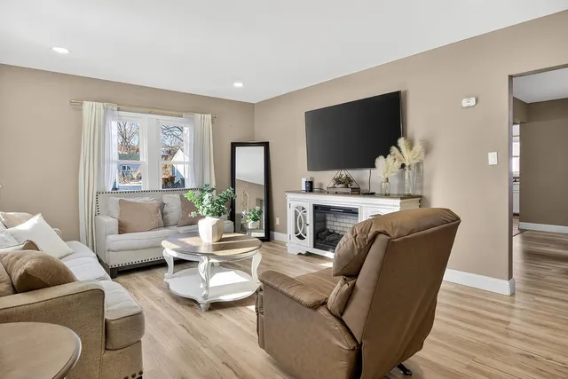 a living room with furniture a flat screen tv and a floor to ceiling window