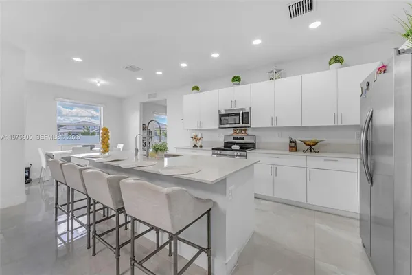 a kitchen with stainless steel appliances a refrigerator sink and white cabinets