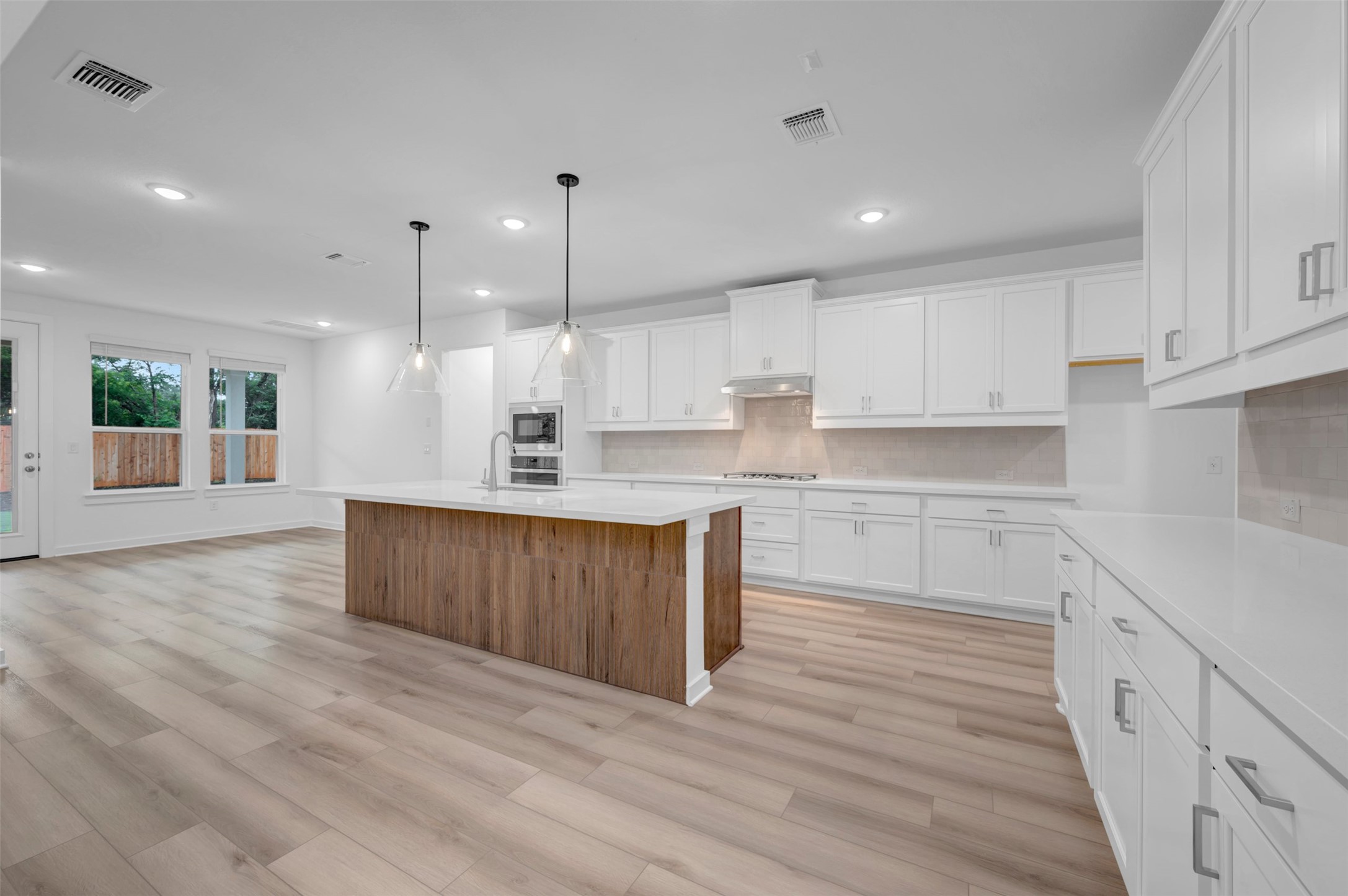 3705 Helena Way Leander, TX 78641 - Photo 18 of 40 a large kitchen with kitchen island a sink wooden floor white stainless steel appliances and cabinets