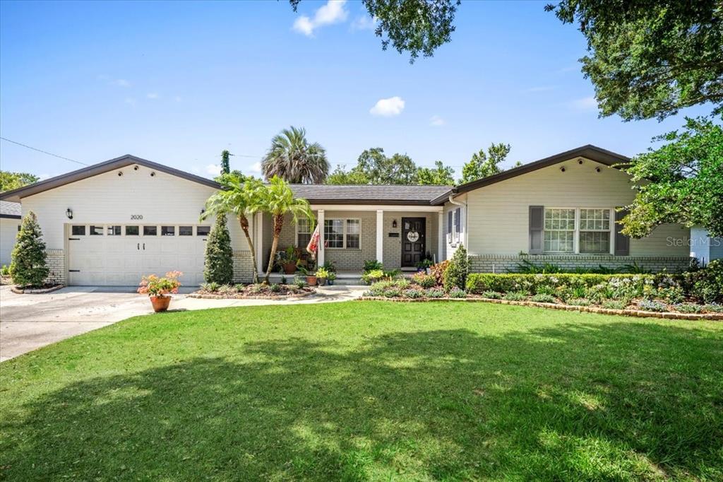 a view of a house with a yard and table and chairs under an umbrella