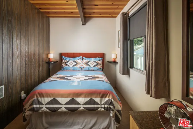a view of a house with wooden fence and large trees
