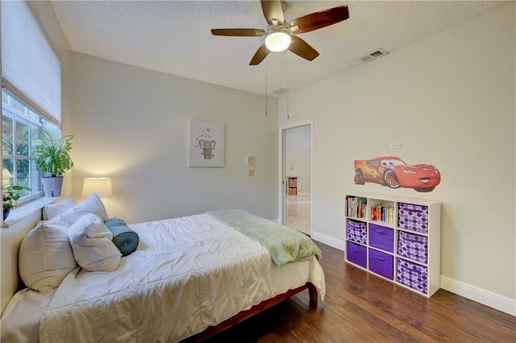8171 Hampton Wood Drive Boca Raton, FL 33433 - Photo 12 of 56 a bedroom with a bed and a chandelier