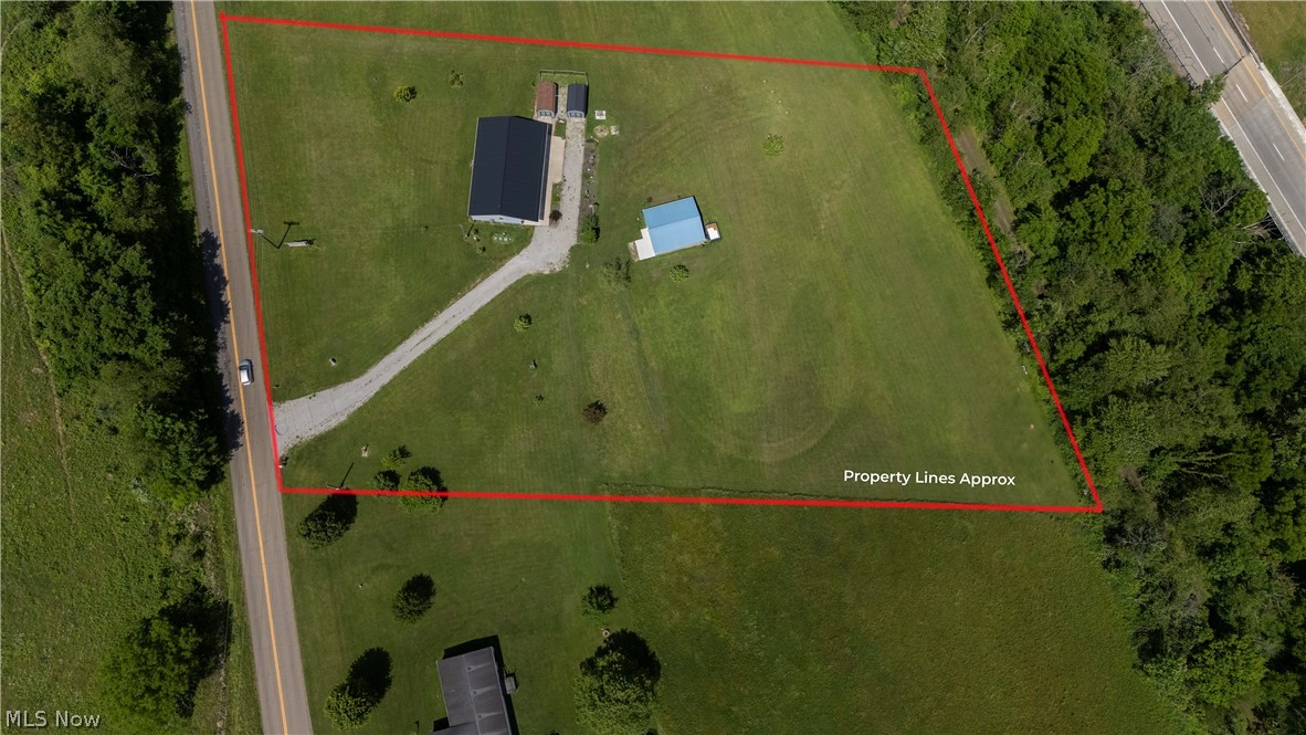 9427 Stonecreek Road Southwest Newcomerstown, OH 43832 - Photo 13 of 29 Expansive lot featuring a main residence with a dark roof, a detached structure with a light blue roof, and a gravel driveway