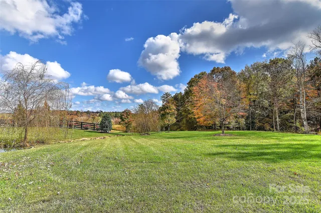 a view of a big yard with swimming pool and brick wall